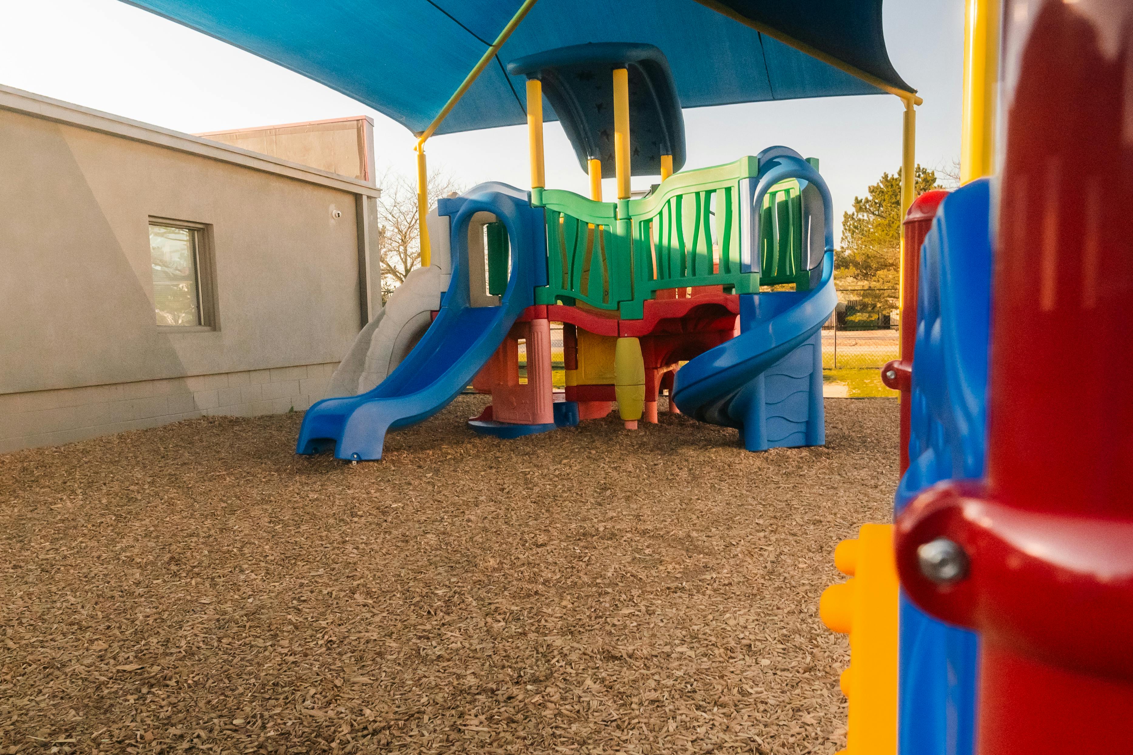 Colorful playground structure with slides under a blue shade canopy