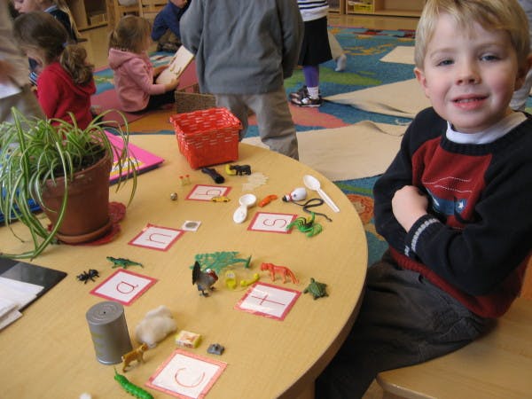 Child sitting at a table with toys and learning cards