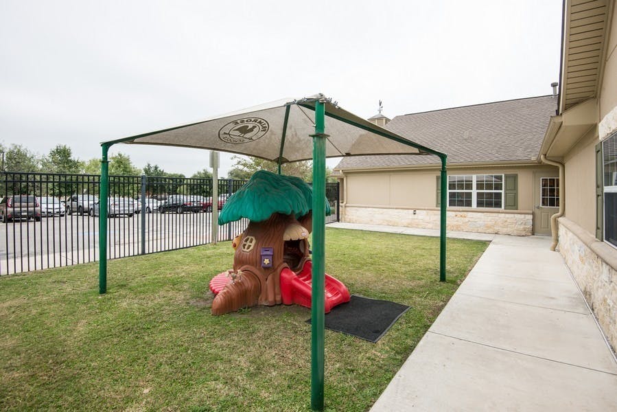 Playground with a small playhouse and slide under a shade canopy