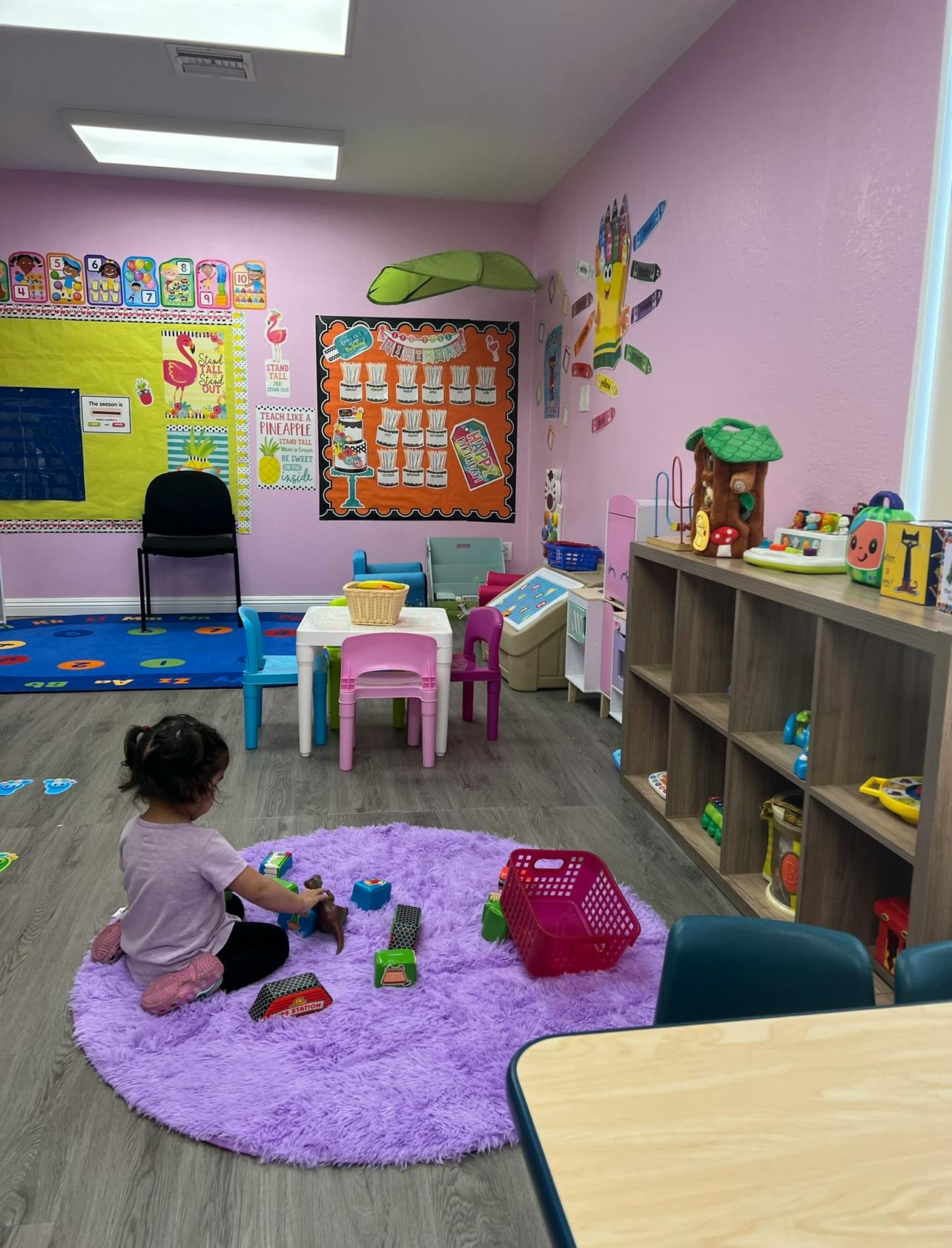 Child playing with blocks on a purple rug in a classroom