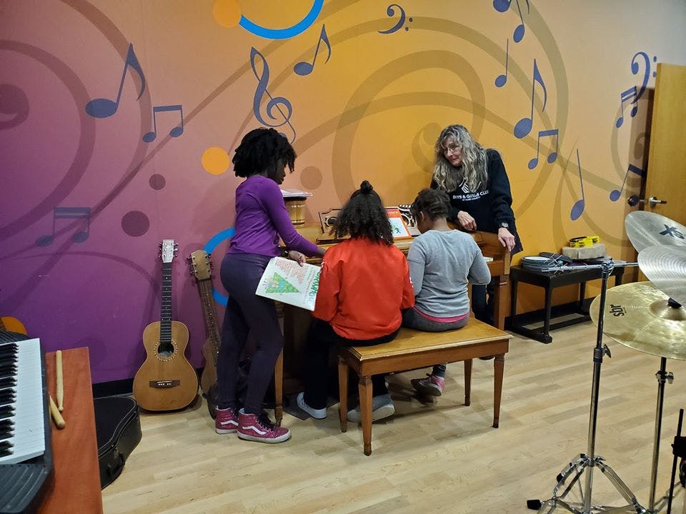 Adult and children in a music room with instruments