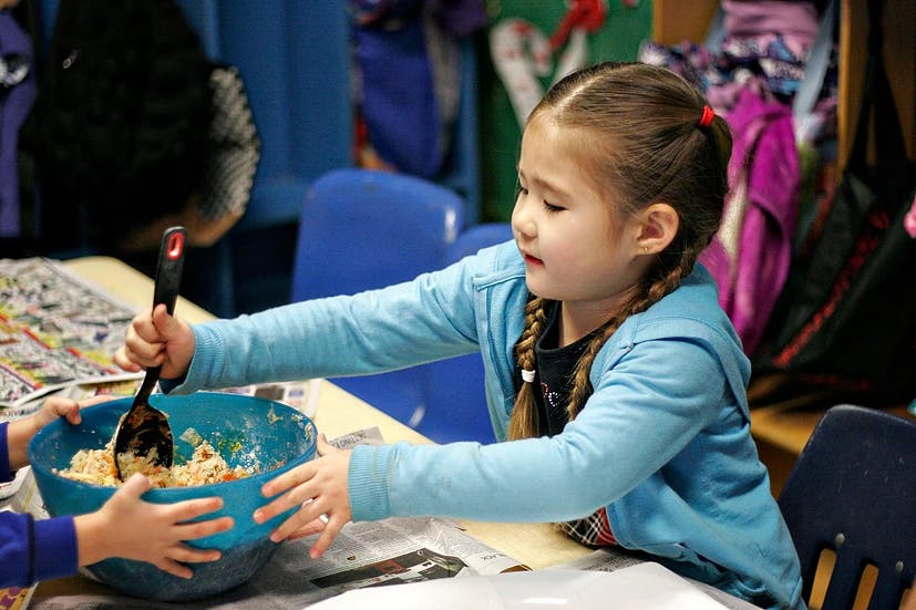 Child stirring a bowl of food with a spoon