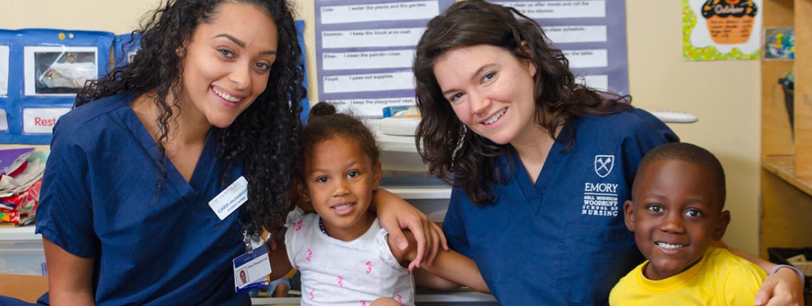 Two people in scrubs with two children