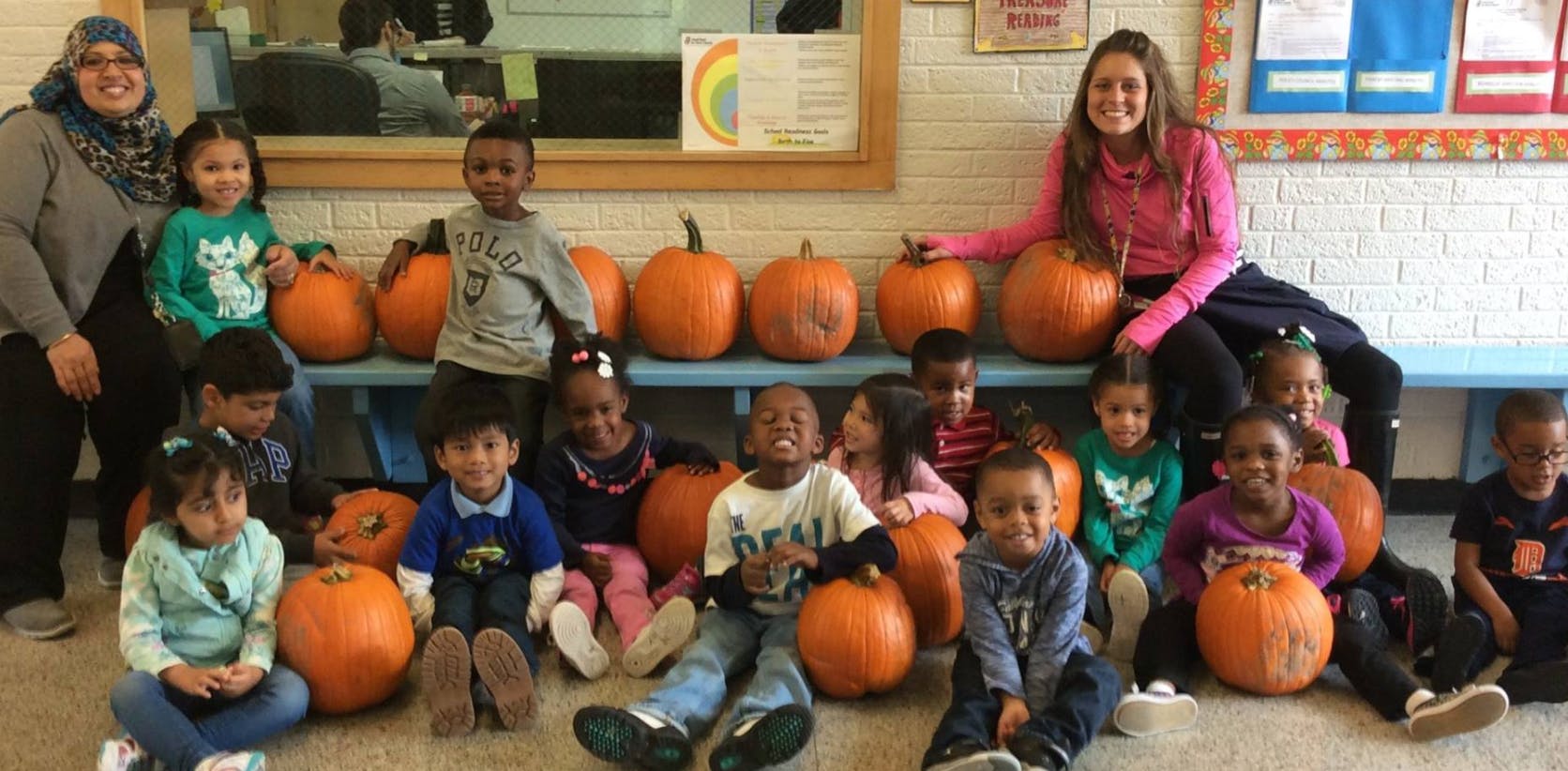 Two people and multiple children with pumpkins
