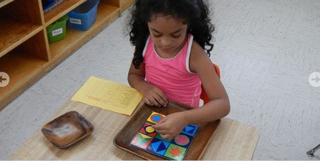 Child playing with a colorful shape puzzle at a table