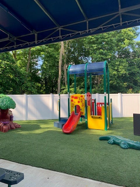 Playground with a slide, climbing structure, and artificial turf
