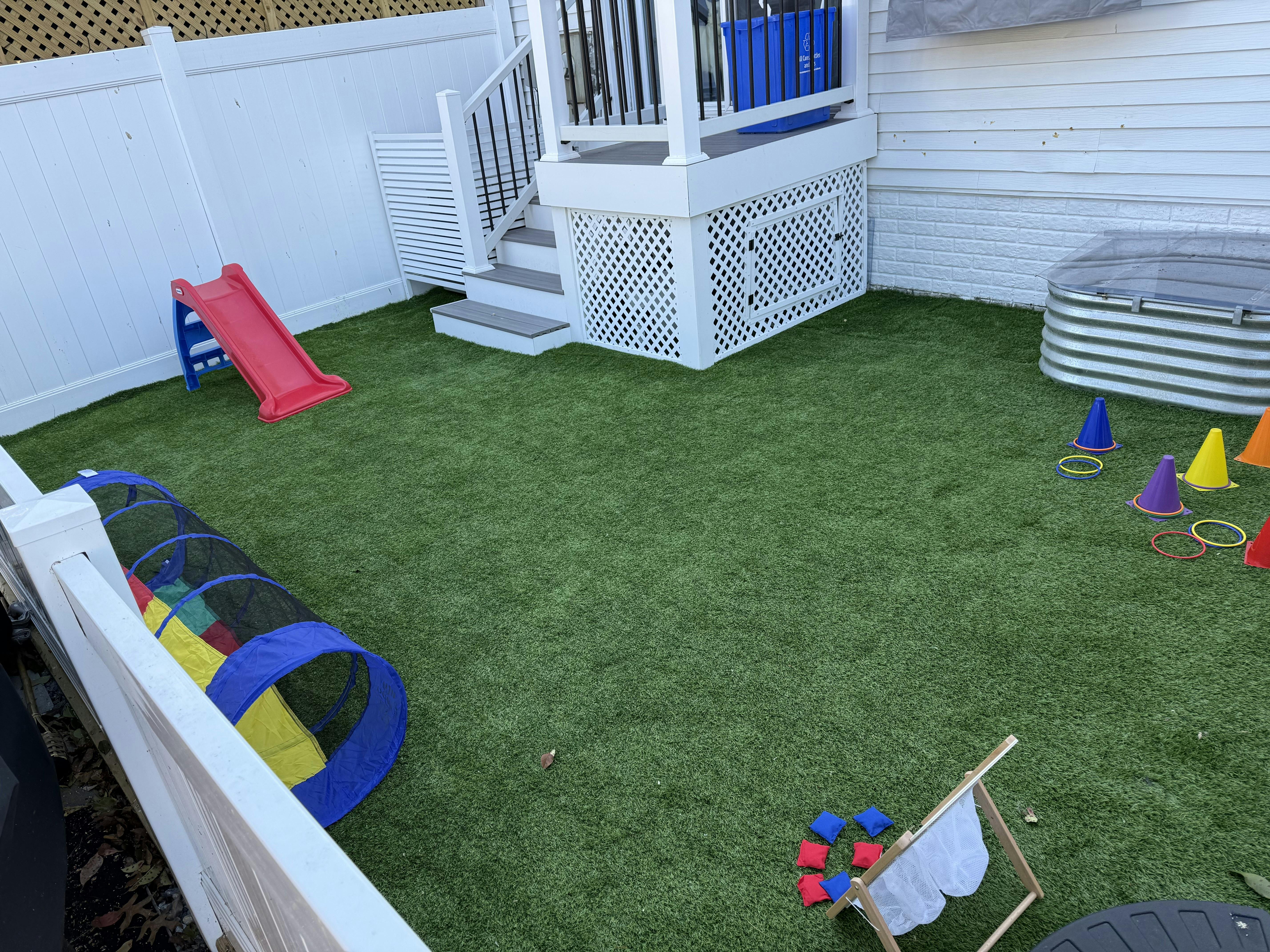 Outdoor play area with artificial turf, slide, and tunnel