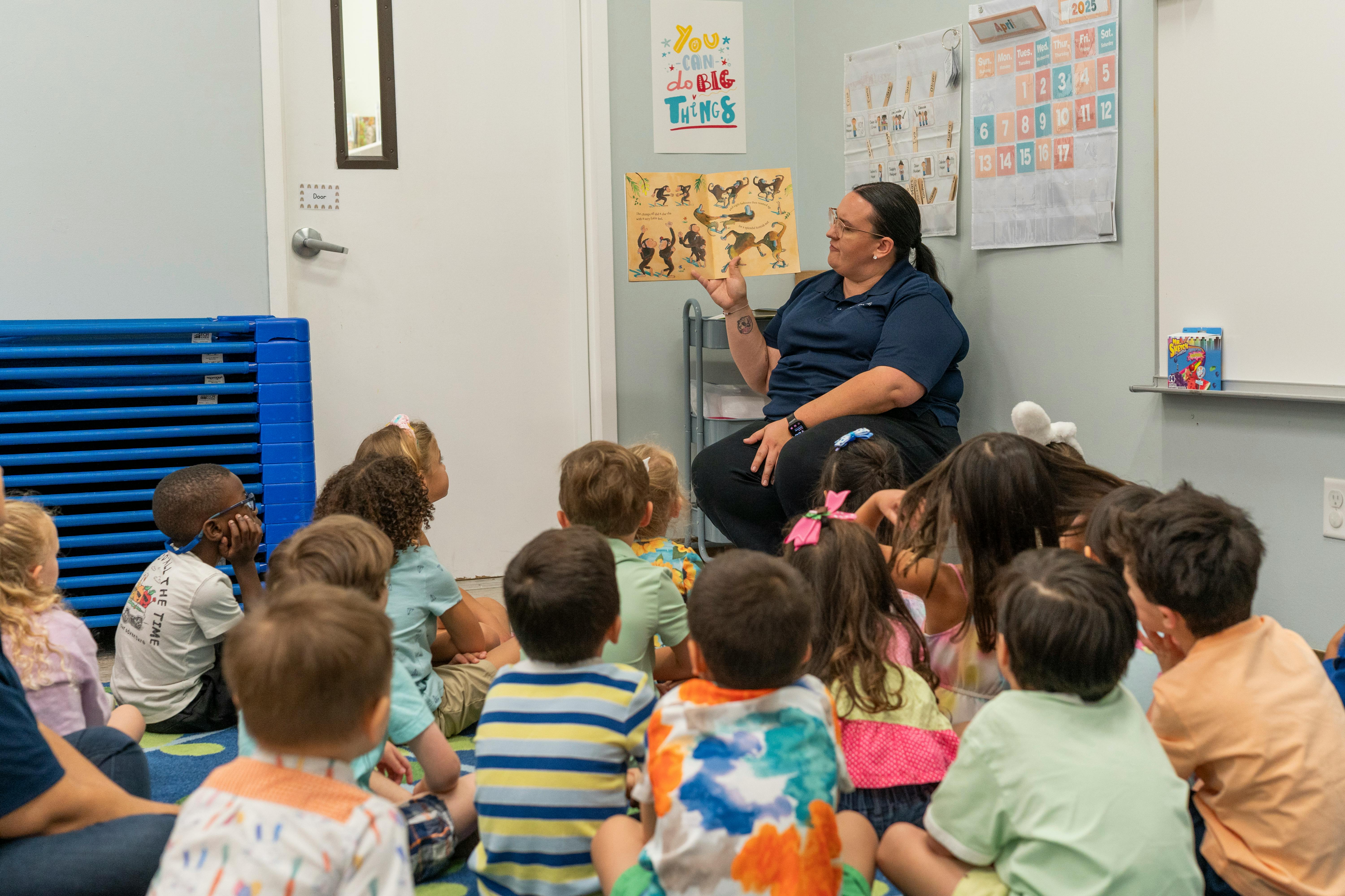 Adult reading to a group of children in a classroom