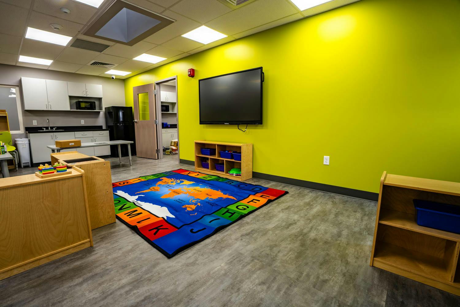 Classroom with map rug, interactive screen, and kitchenette