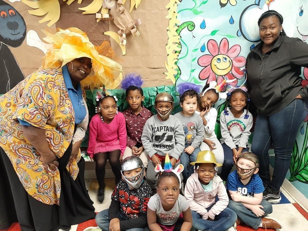 Two people with a group of children, some wearing costumes