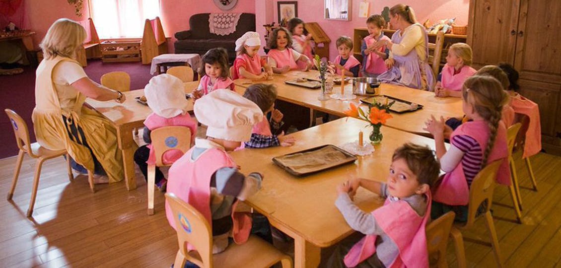 Adult and children sitting at tables in a classroom