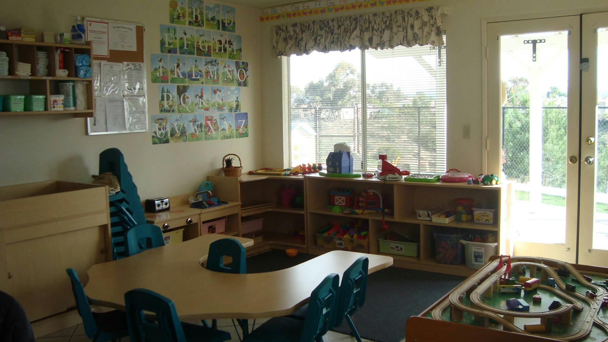 Classroom with tables, chairs, and shelves with toys