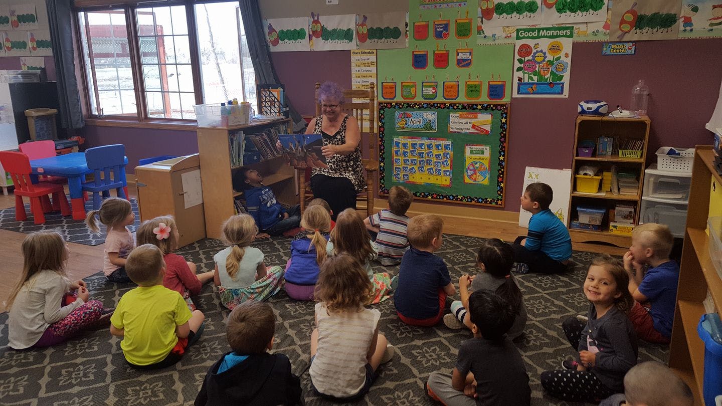Person reading to a group of children in a classroom