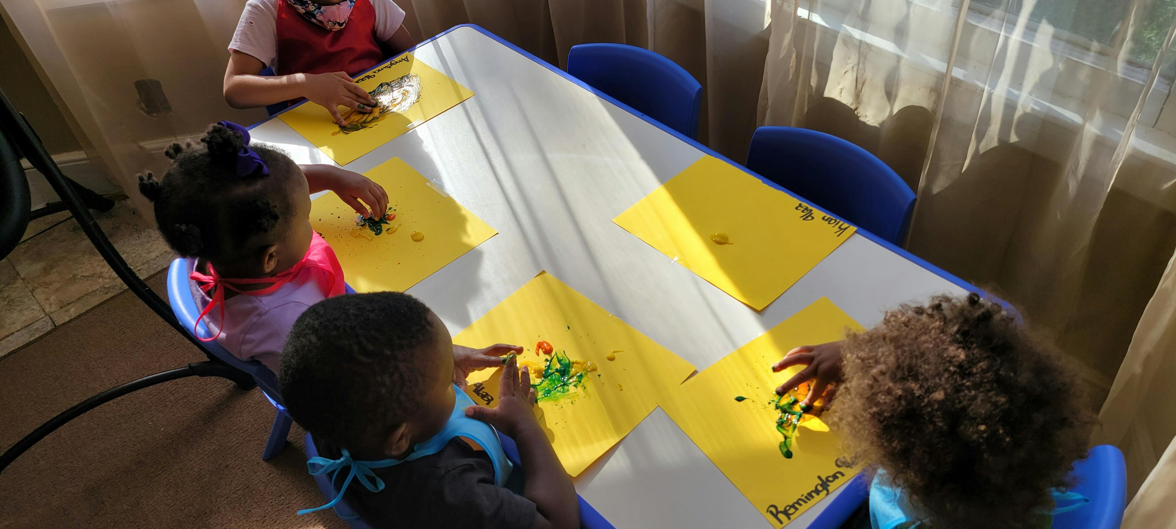 Children at a table with yellow papers and white placemats