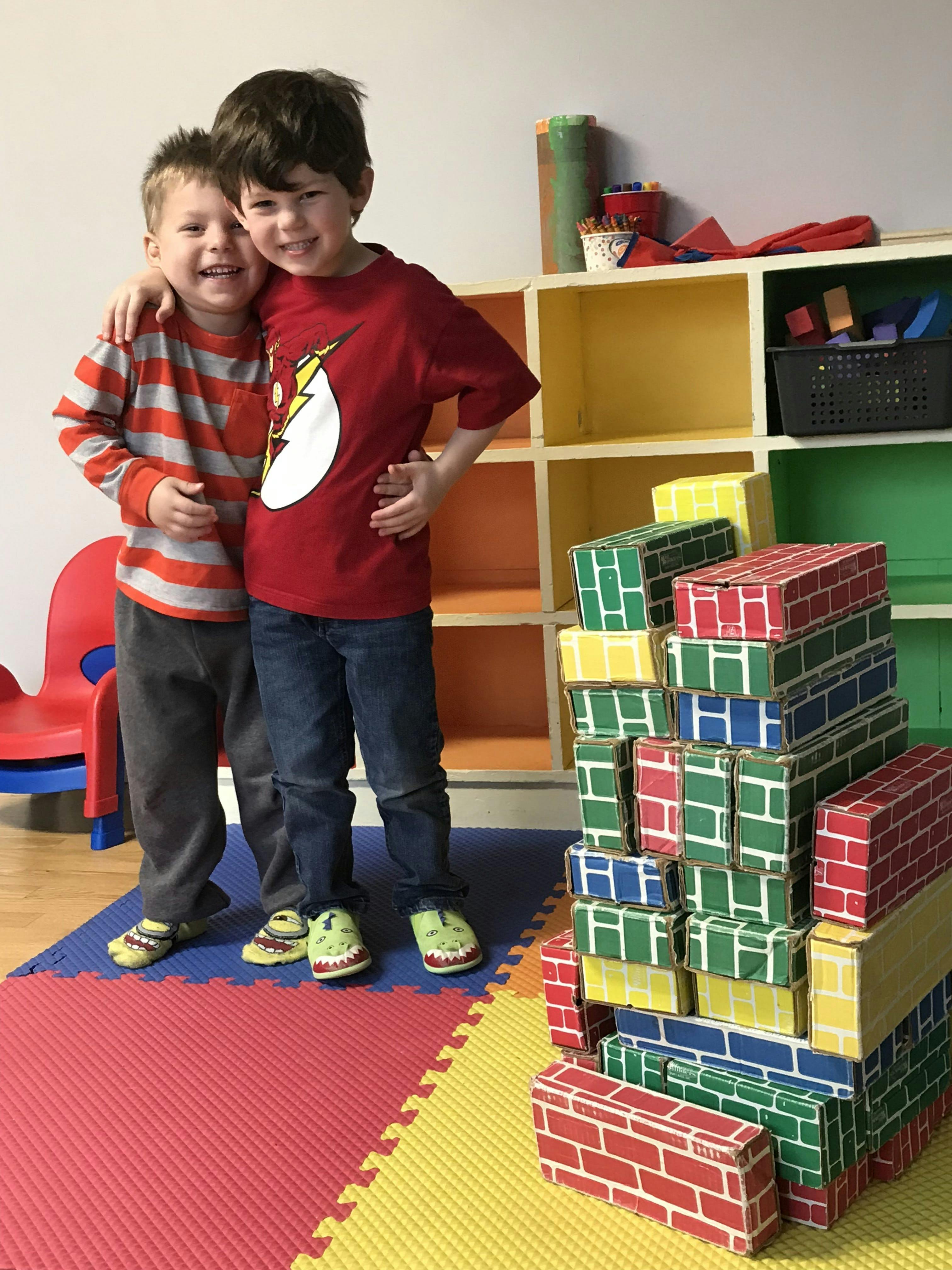 Two children standing with arms around each other in a classroom