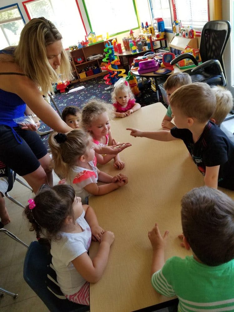 Adult and children gathered around a table in a classroom