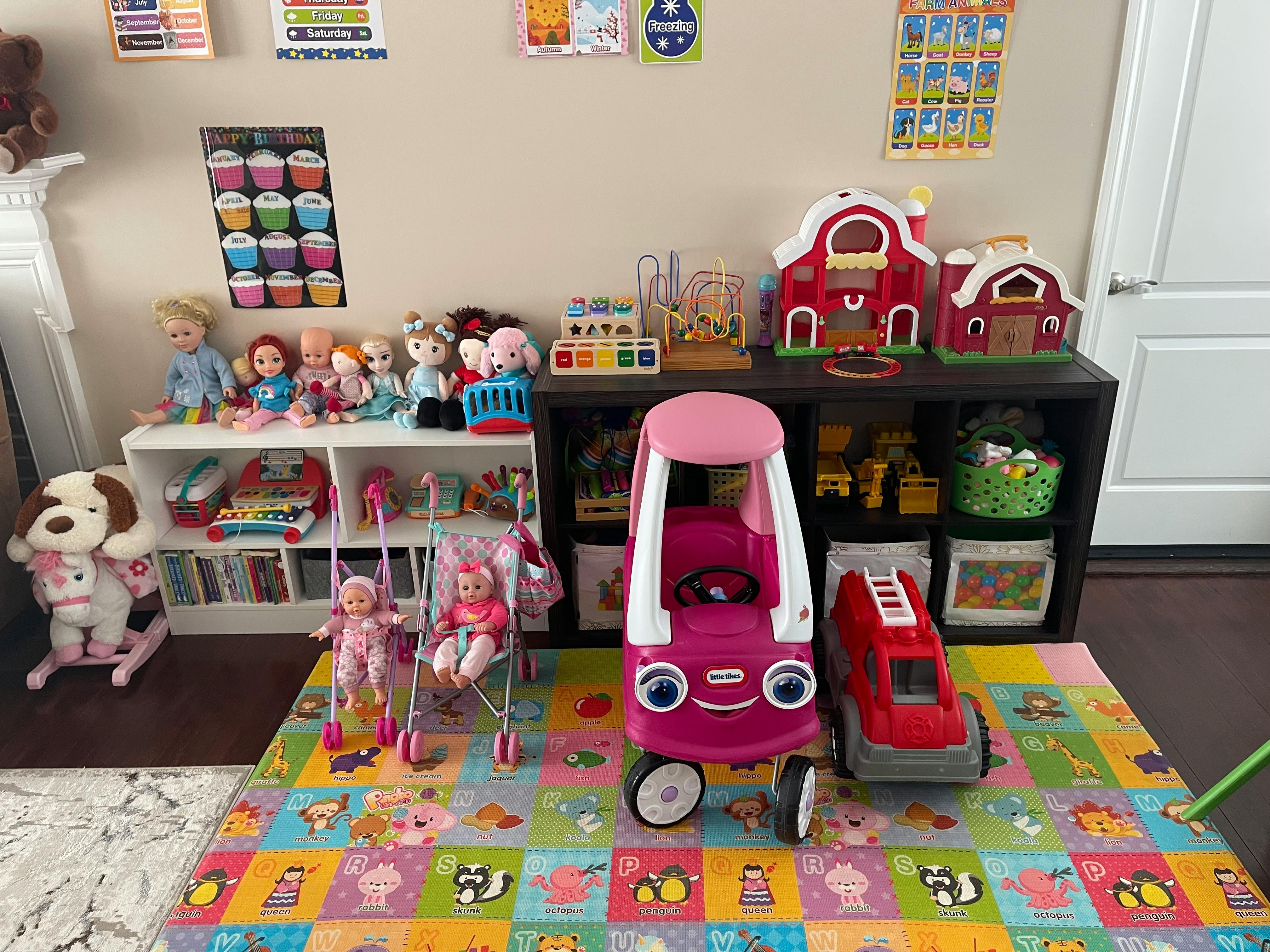 Children's toys including dolls, doll strollers, and ride-on cars in a room