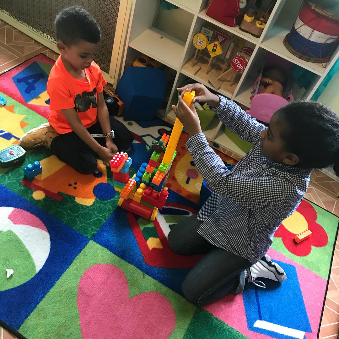 Two children playing with building blocks on a colorful rug