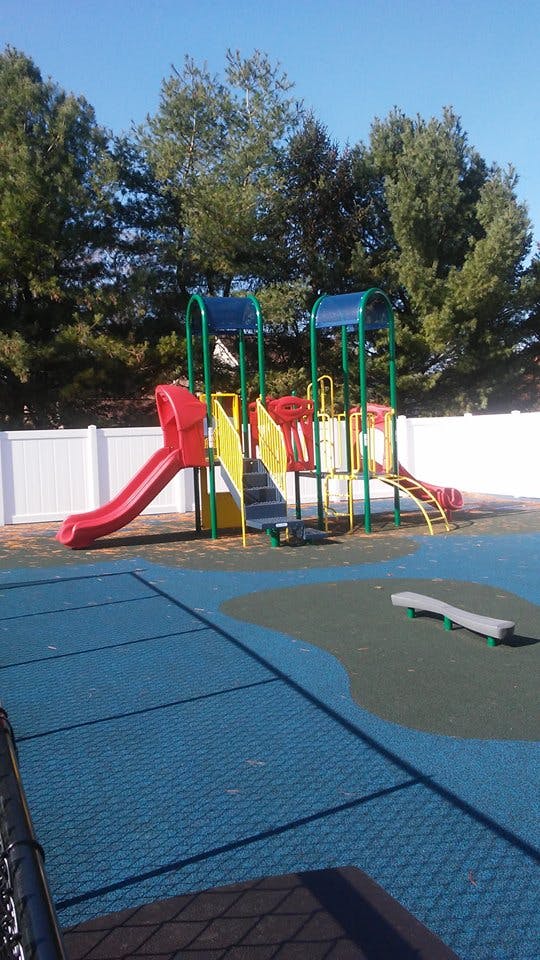 Playground with slides and climbing structures on a blue padded surface