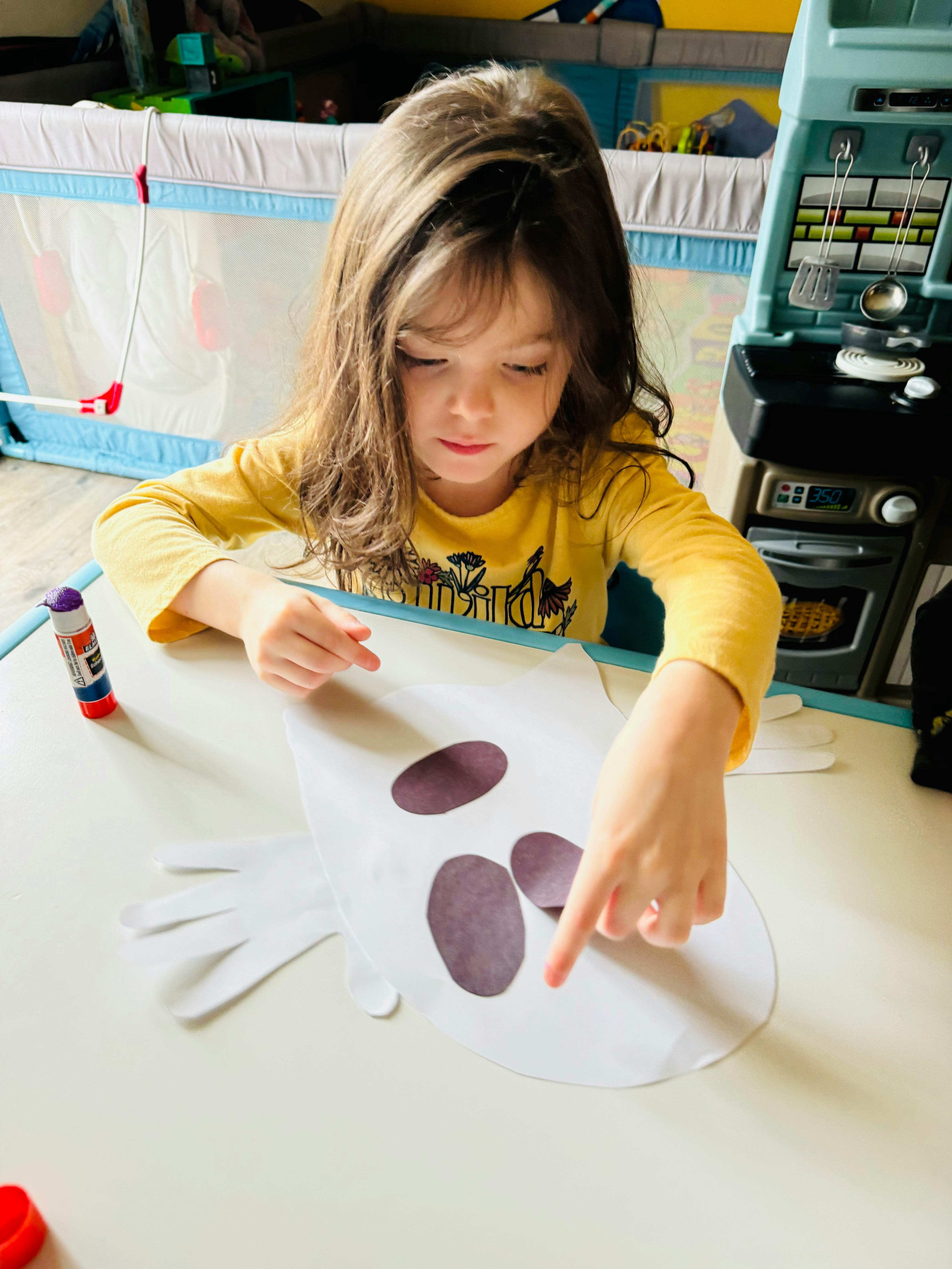 Child making a craft with paper cutouts and glue