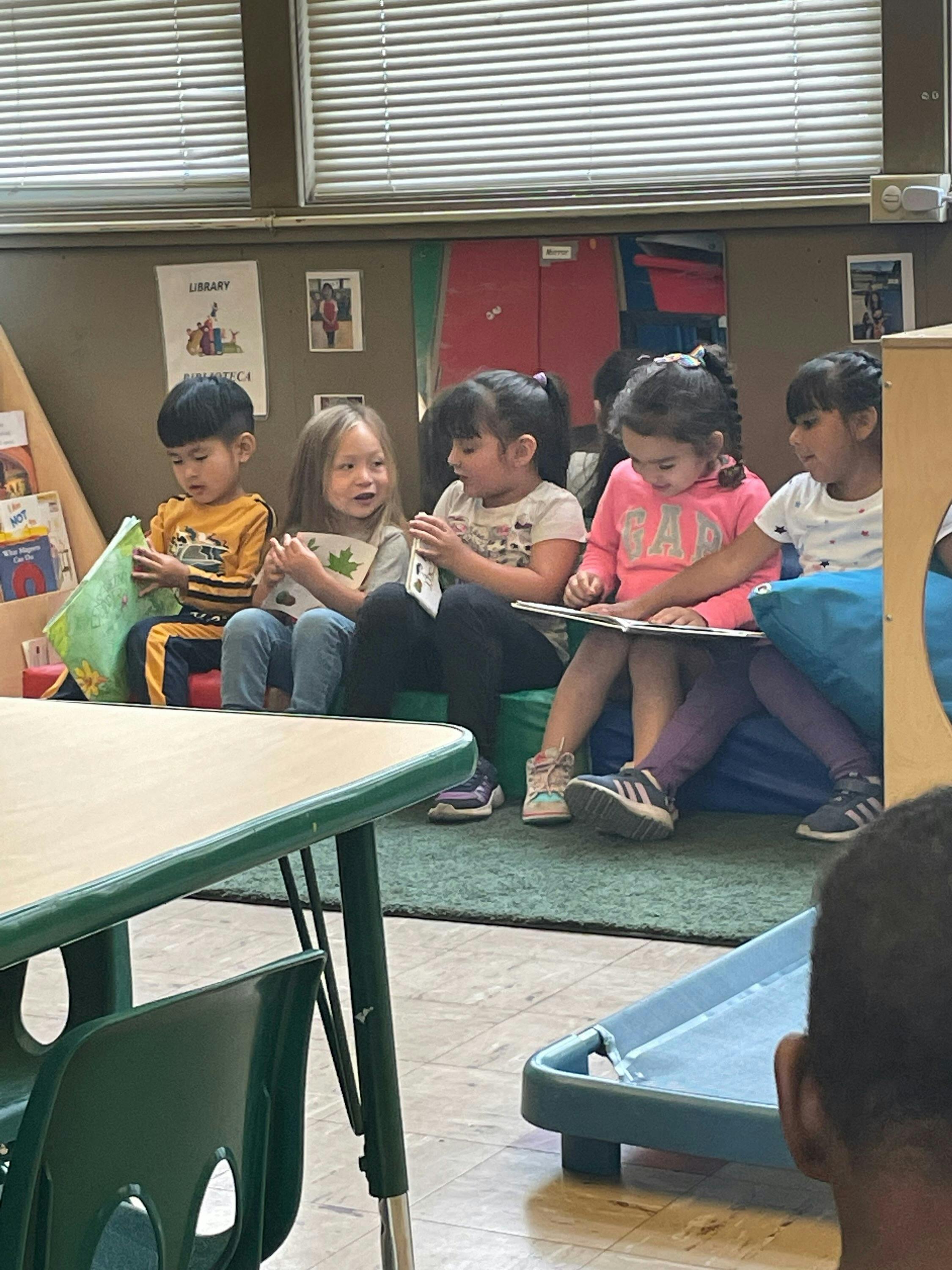 Children sitting on the floor reading books in a classroom