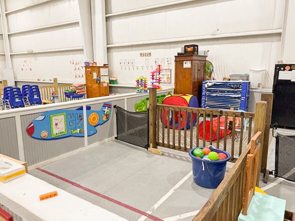 Indoor play area with a fenced-in section containing toys and tunnels