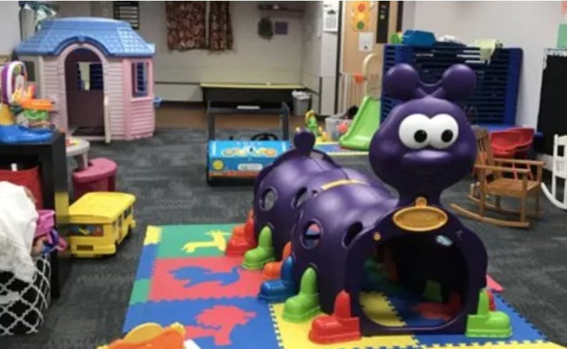 Playroom with a purple caterpillar tunnel and a pink playhouse