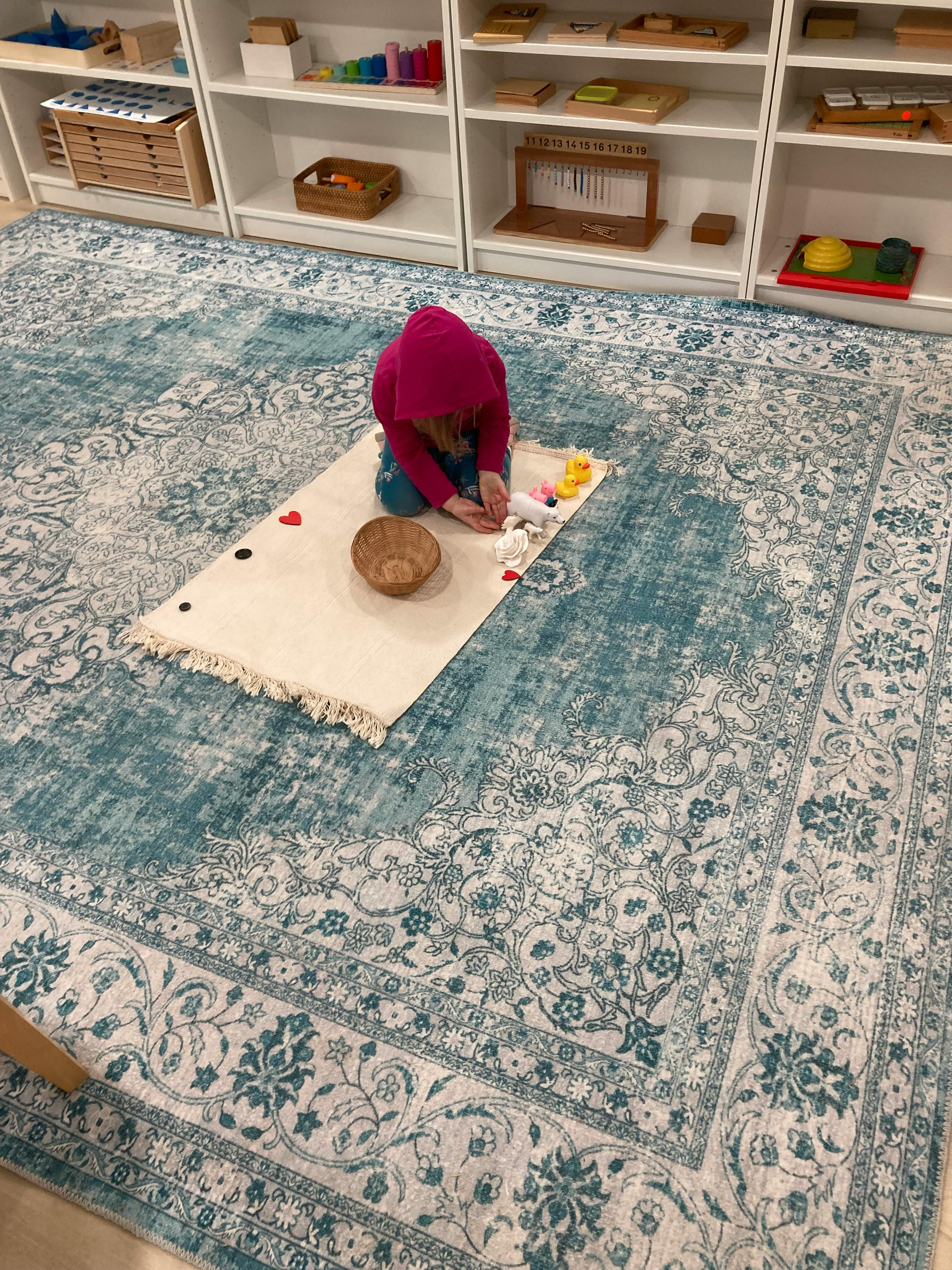 Child kneeling on a mat, interacting with small objects