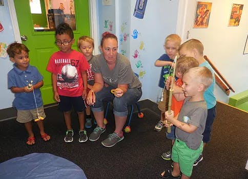 Adult and children gathered in a classroom, some holding toys
