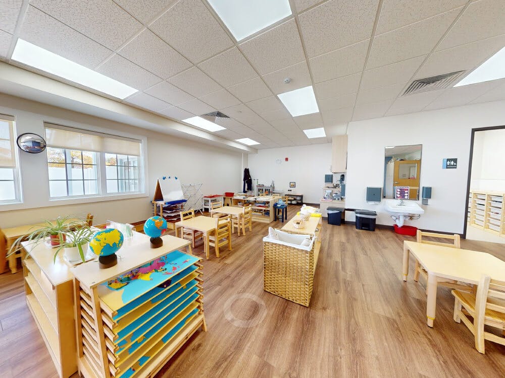Empty classroom with small tables, chairs, and learning materials