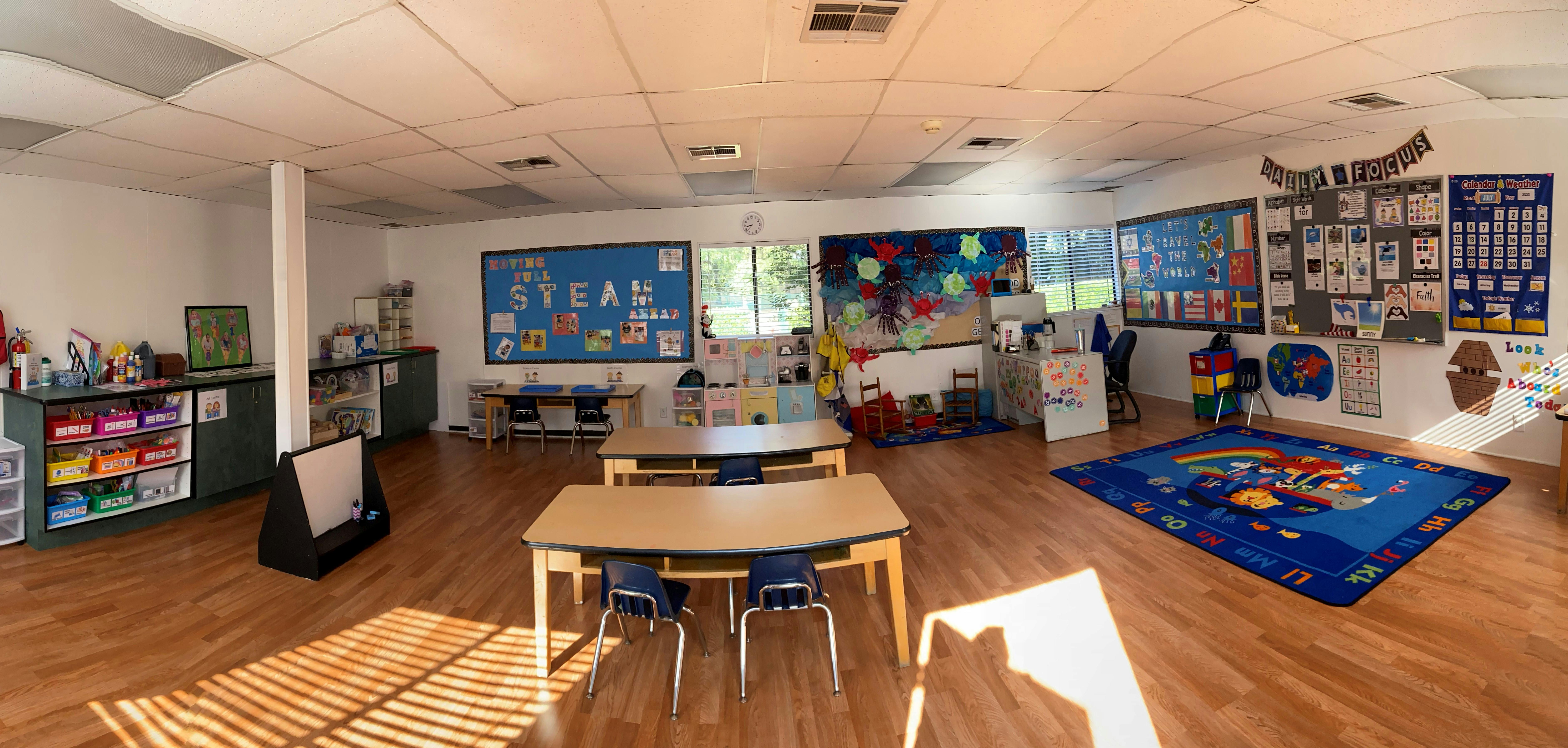 Empty classroom with small tables and chairs, colorful decorations on walls