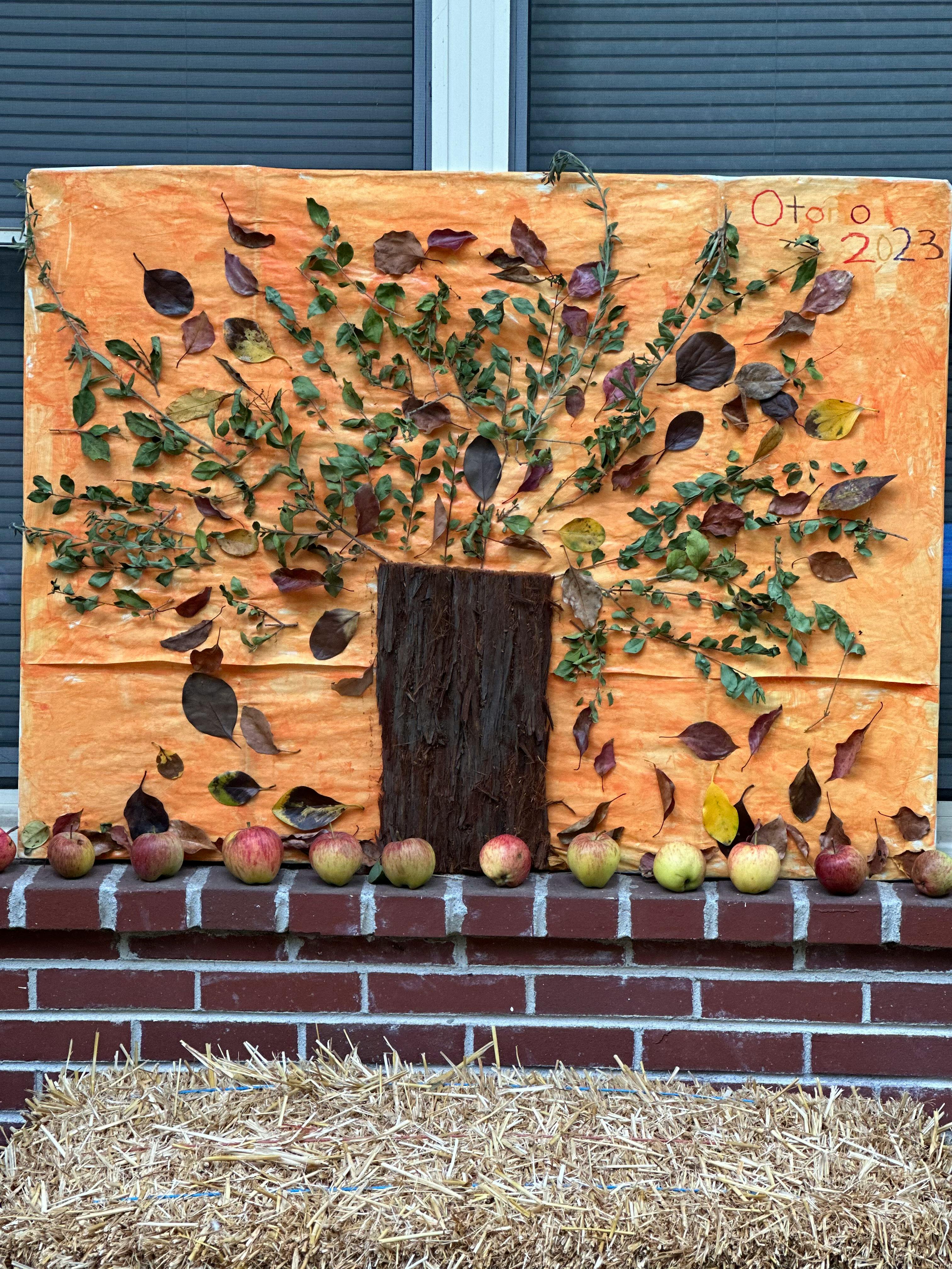 Autumn 2023 sign with a tree made of leaves and apples on a brick ledge