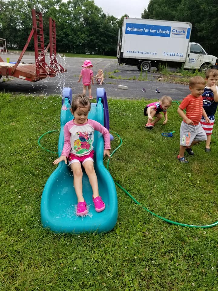 Child sitting on a blue water slide with water spraying