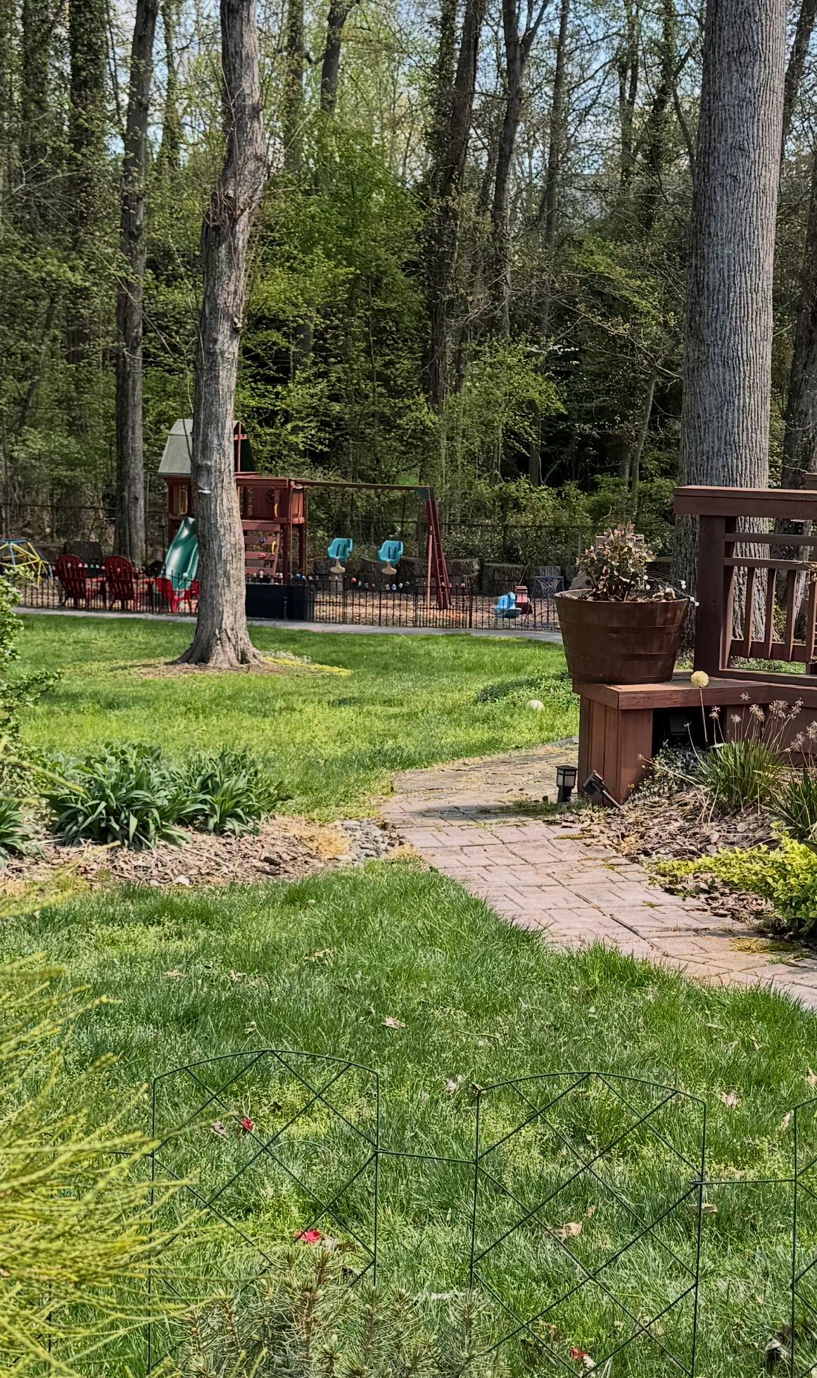 backyard with a wooden playset, swings, and a slide behind a fence