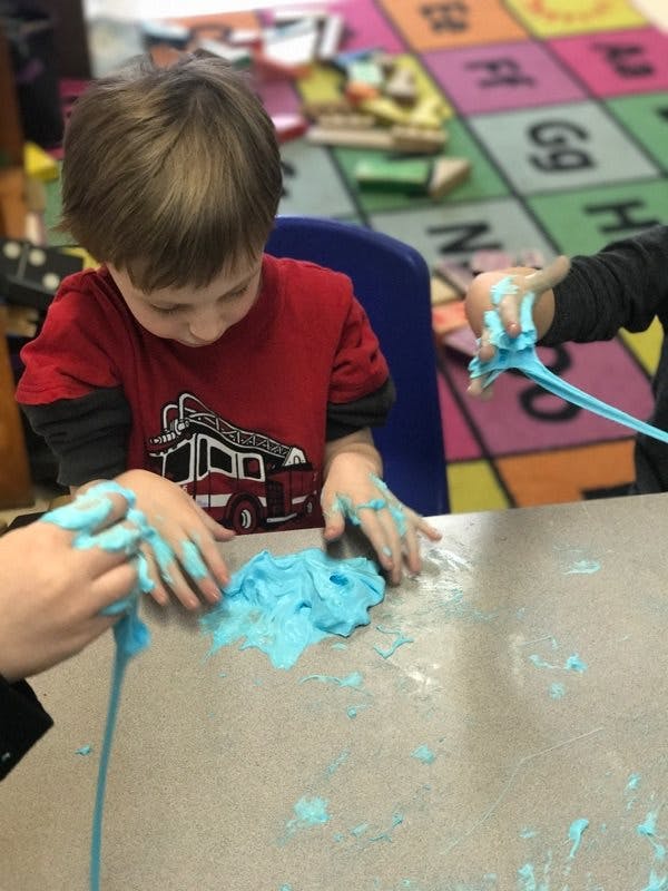 Child playing with blue slime at a table