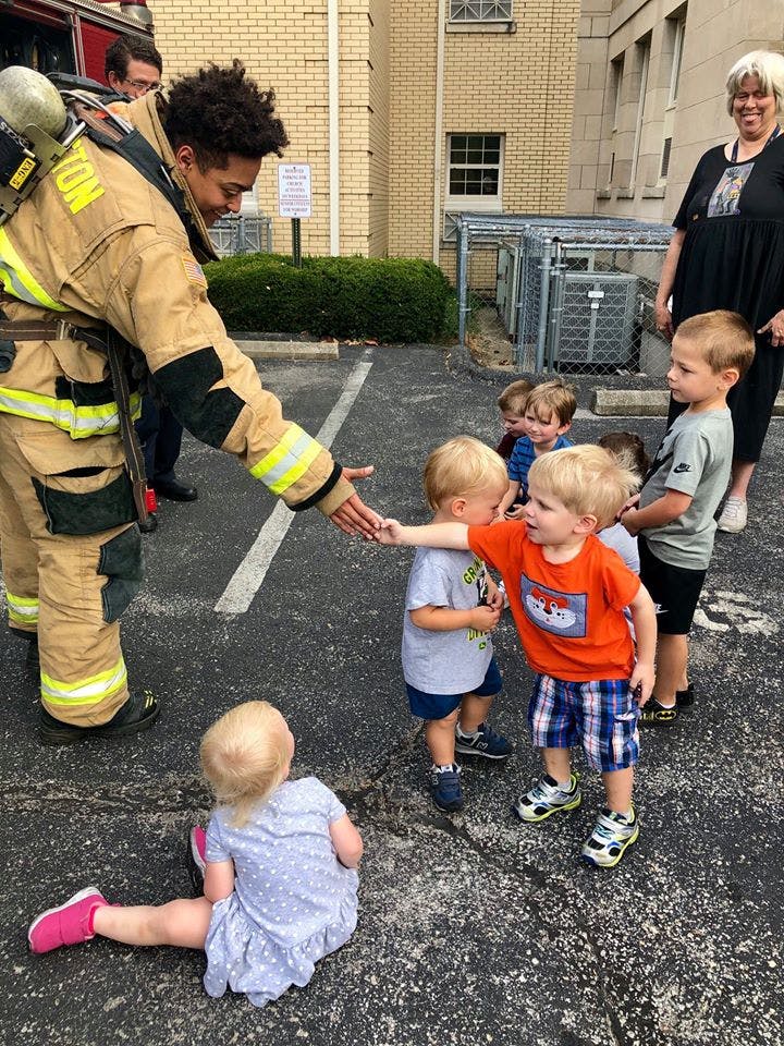 Firefighter in uniform reaching out to shake hands with a child