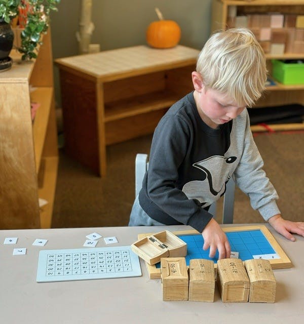Child placing a number tile into a blue grid