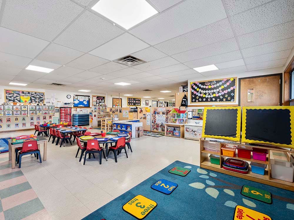 Empty classroom with small tables and chairs, and learning decorations on walls