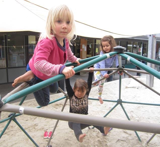 Three children playing on a jungle gym