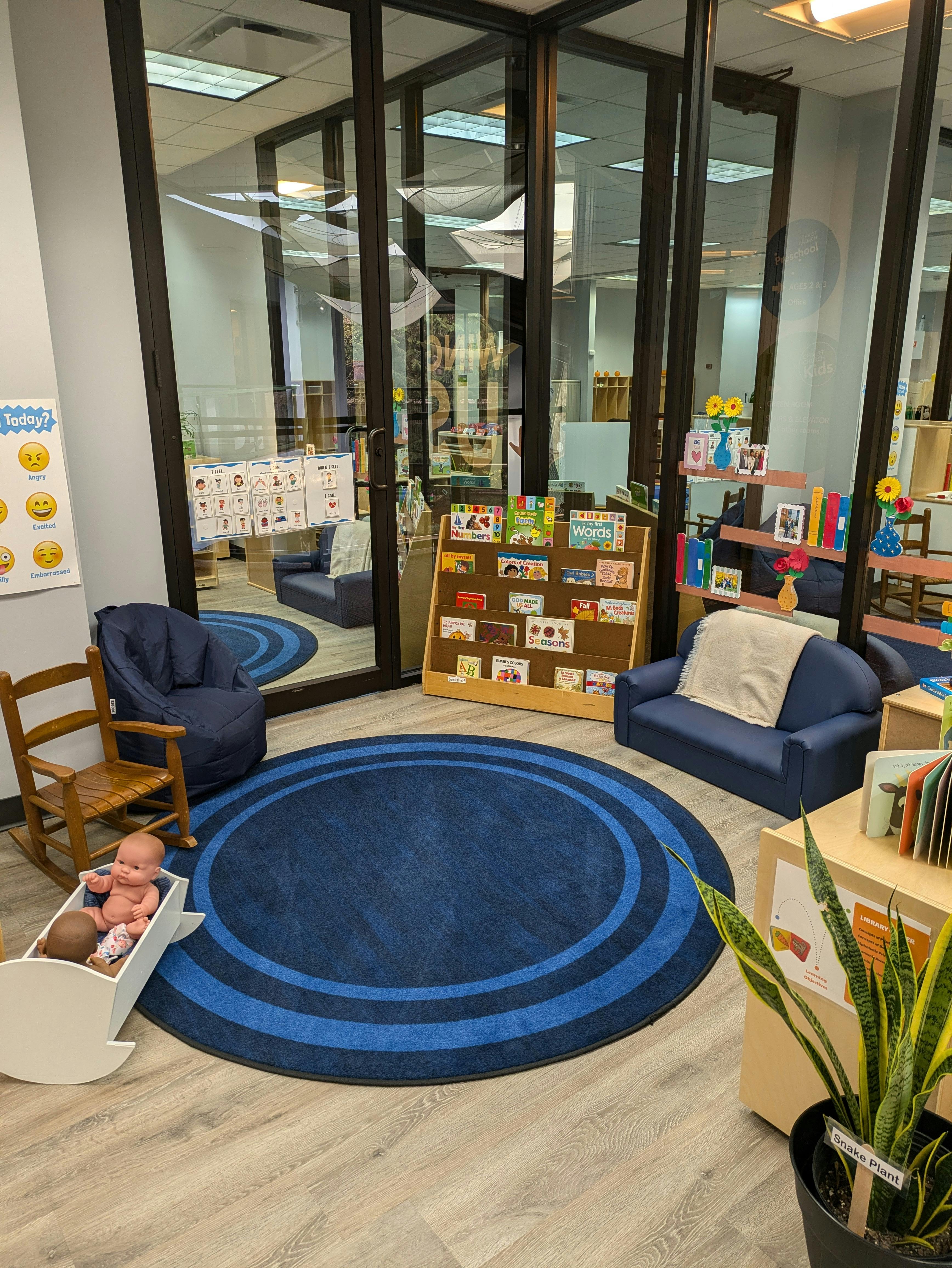 Classroom with blue rug, chairs, and bookshelves