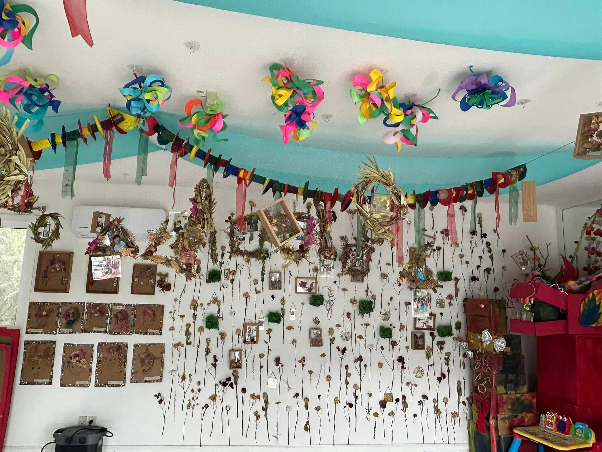 Wall decorated with various crafts, garlands, and small pictures