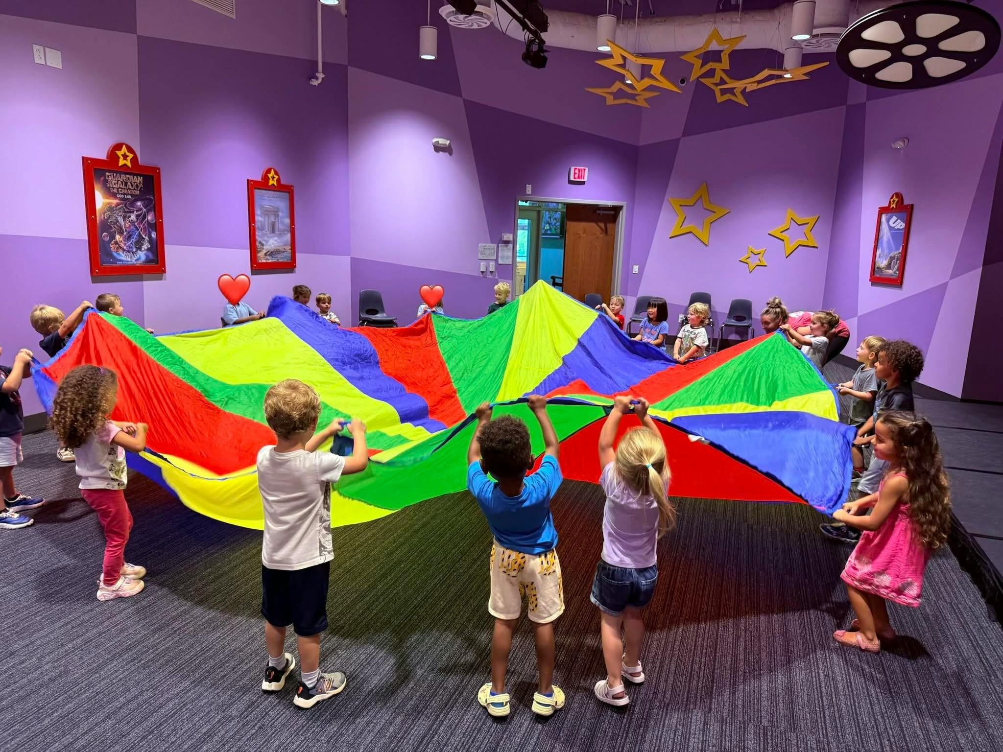 Group of children holding a colorful play parachute in a room