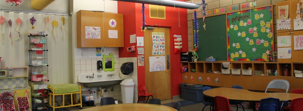 Classroom with a sink, door, chalkboard, and tables