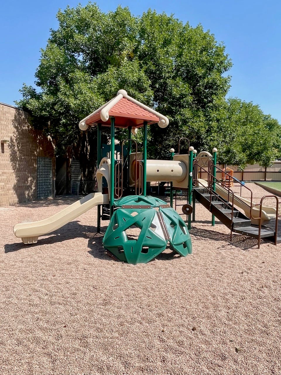 Playground with slides, climbing dome, and stairs on wood chips