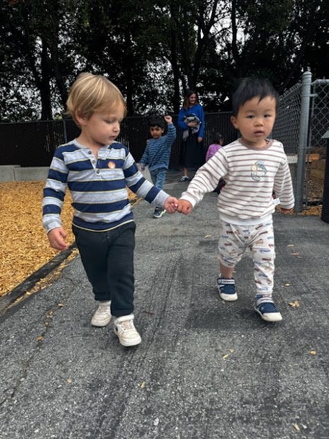 Two children holding hands and walking outdoors