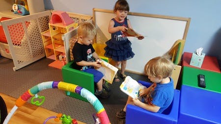 Three children reading books in a classroom