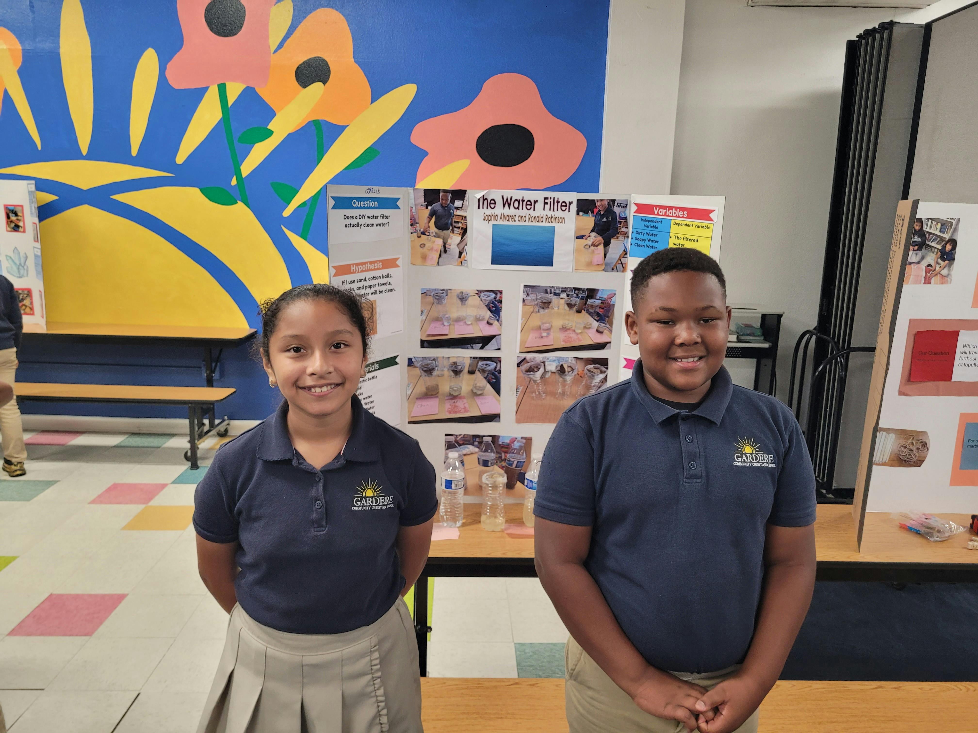 Two teens standing in front of a science fair project display