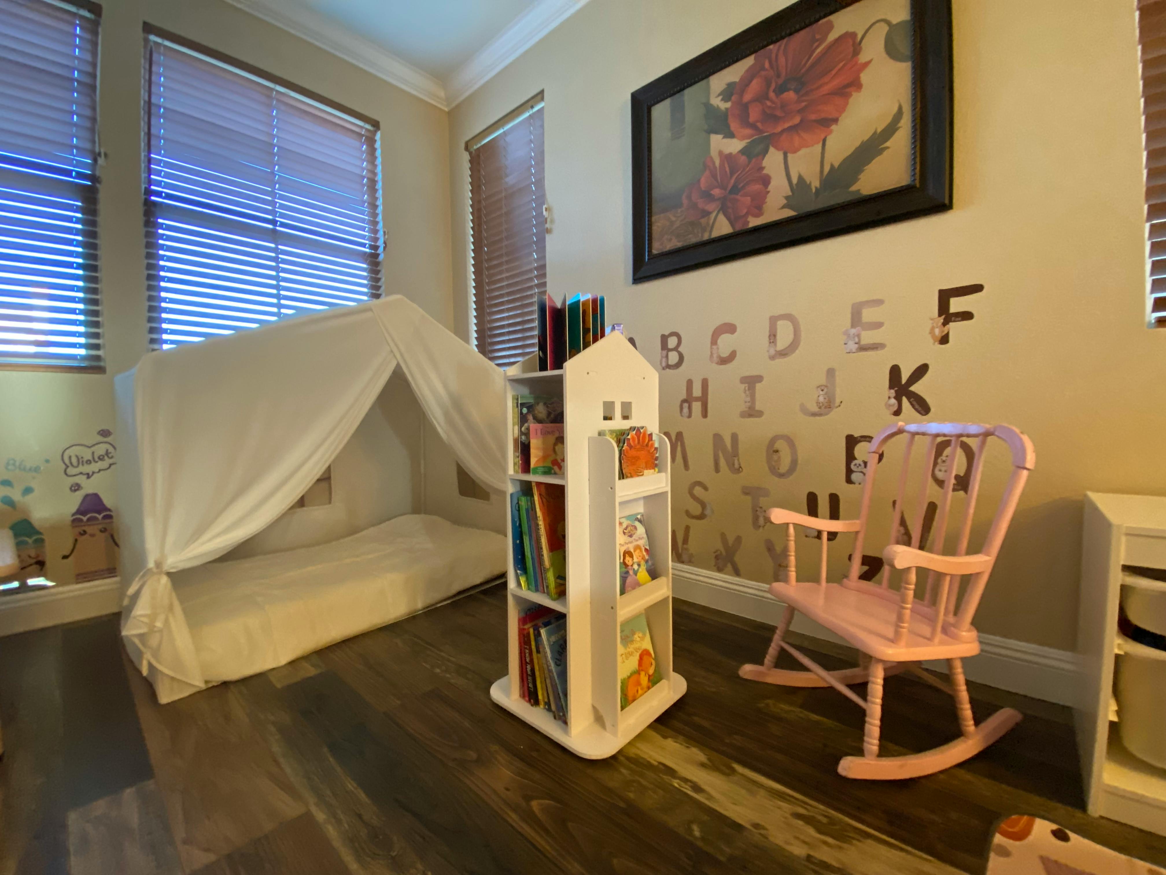 Child's room with a canopy bed, bookshelf, and rocking chair