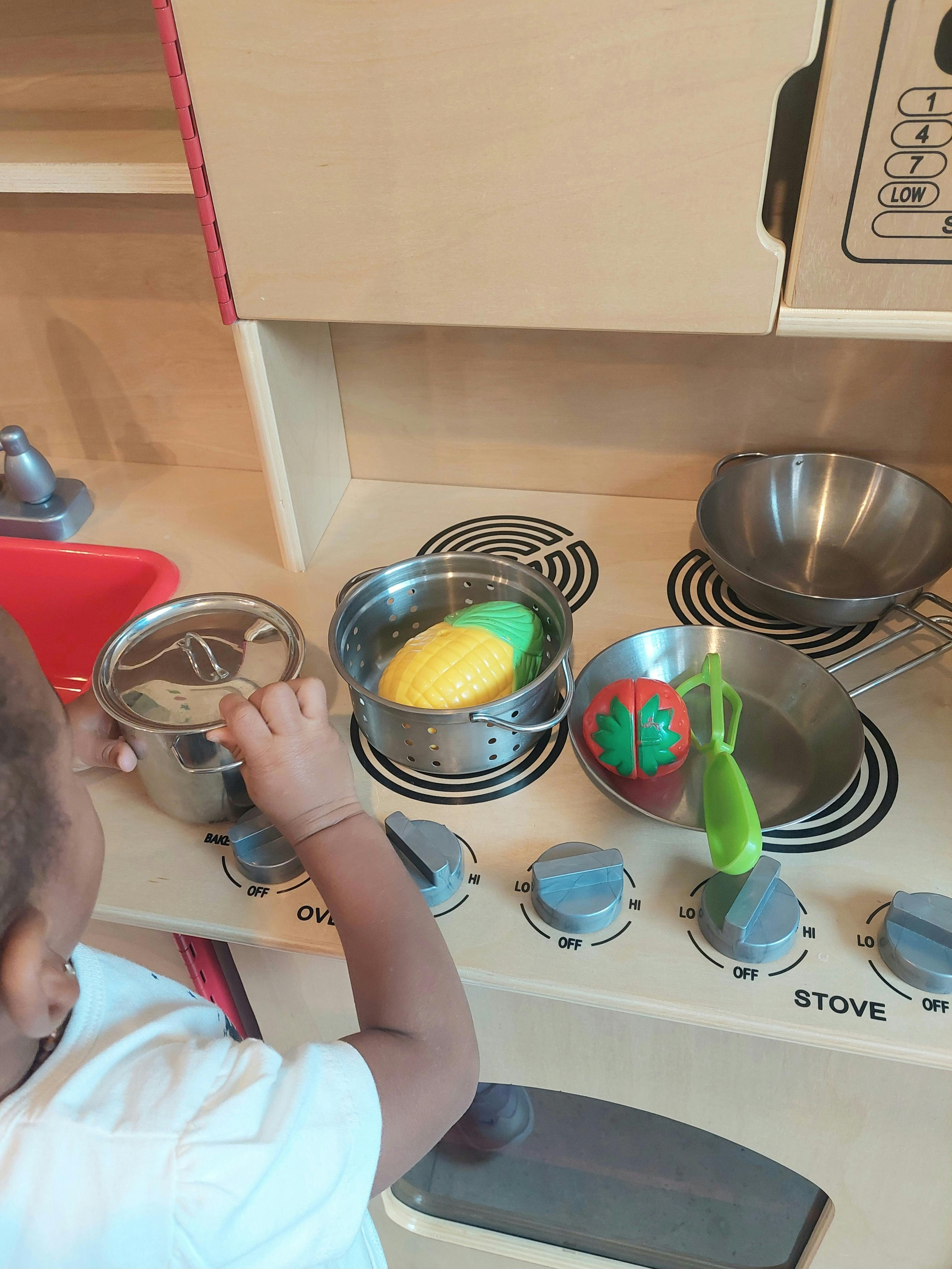 Child playing with toy kitchen set and pots