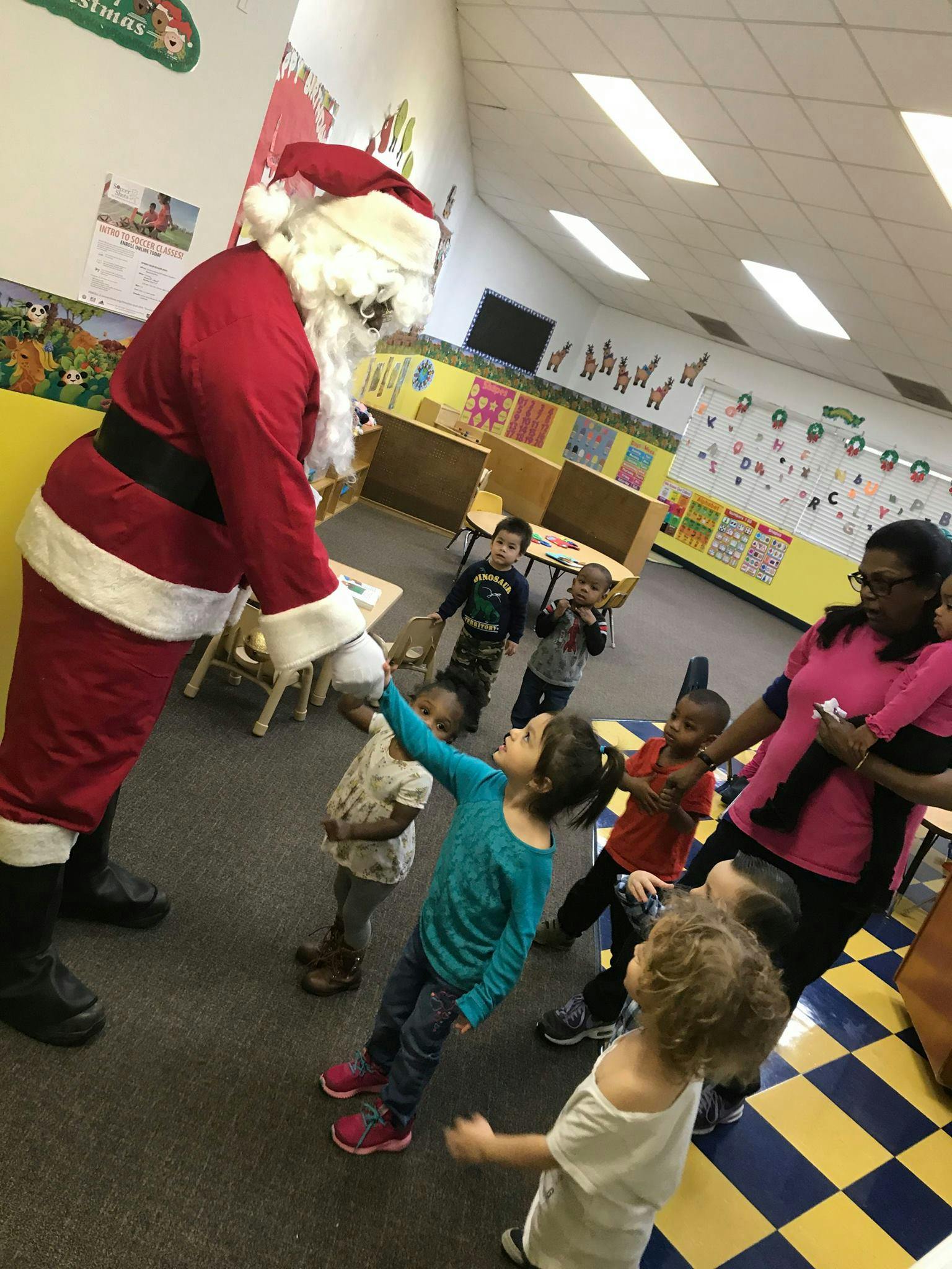 Person dressed as Santa Claus interacting with children in a classroom